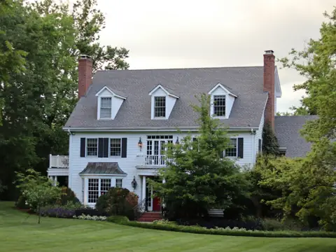 White colonial home with a slate-gray roof and dormers